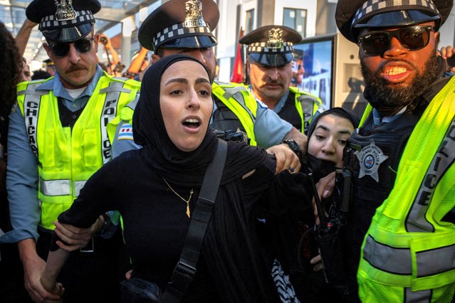 Women wearing hijab, who were photographing a pro-Palestinian protest march, are detained by police along the Damen train station platform, on sidelines of the Democratic National Convention in Chicago on August 21, 2024. (Photo by Adrees Latif/Reuters)