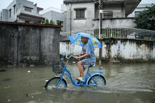 A citizen rides through waterlogged street as torrential rains hit Zhongshan on May 12, 2022 in Zhongshan, Guangdong Province of China. (Photo by VCG/VCG via Getty Images)