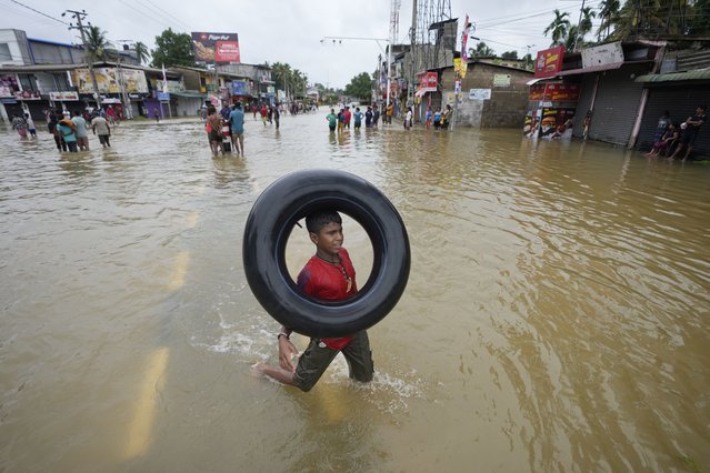 A boy plays with an inflatable rubber tube in a flooded street in Biyagama, a suburb of Colombo, Sri Lanka, Monday, June 3, 2023. Sri Lanka closed schools on Monday as heavy rains triggered floods and mudslides in many parts of the island nation, killing at least 10 people while six others have gone missing, officials said. (Photo by Eranga Jayawardena/AP Photo)