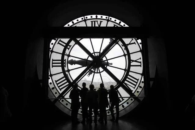 Visitors at the Musee d'Orsay are seen in silhouette as they look behind a giant clock face at the former Orsay railway station, in Paris, France July 28, 2015. The national museum of the Musee d'Orsay opened in December 1986 and it displays collections of art from the period 1848 to 1914.  France has been the world's most visited country since the 1980's, welcoming 84 million tourists last year. (Photo by Stephane Mahe/Reuters)