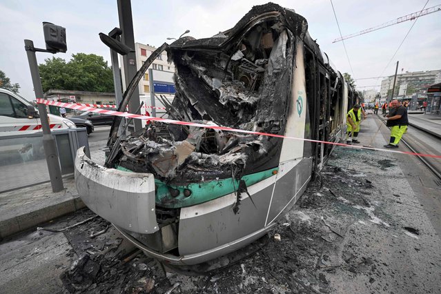 Workers sweep up the debris of a burnt tram destroyed during protests the previous night in Clamart, southwest of Paris, on June 29, 2023. Protests erupted across the greater Paris region that saw protesters burn cars, lorries and trams in reaction to the shooting by police of a 17-year-old boy at point-blank range on June 27, 2023, in Nanterre, Paris, in an incident that has reignited debate in France about police tactics long criticised by rights groups over the treatment of people in low-income suburbs, particularly ethnic minorities. (Photo by Emmanuel Dunand/AFP Photo)