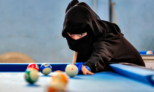 A woman plays billiards during a local championship at a sports hall in Yemen's capital Sanaa on December 16, 2019. (Photo by Mohammed Huwais/AFP Photo)