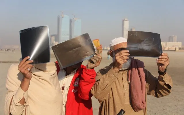 Pakistani people use an ultra-violet paper to observe the solar eclipse in Karachi, Pakistan, on December 25, 2019.The darkest day across Asia as an annular eclipse of the sun has started and is visible in Pakistan for the first time in 20 years, according to the Pakistan Meteorological Department. (Photo by Sabir Mazhar /Anadolu Agency via Getty Images)