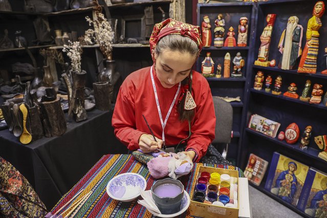 A Russian folk artist paints her self-made traditional Russian wooden toy during the XXIII exhibition and fair of Russian folk arts and crafts “Firebird. Autumn 2024” in Moscow, Russia, 02 October 2024. The withdrawal of Western companies from Russia following global sanctions imposed on the country due to the start of Russia's Special Military Operation in Ukraine starting in February 2022 led to increased demand for goods from Russian craftsmen, artisans, and local farms. (Photo by Sergei Ilnitsky/EPA/EFE)