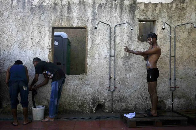 A migrant from Pakistan (R) has a shower as others wash their clothes at a deserted hotel on the Greek island of Kos, August 13, 2015. (Photo by Alkis Konstantinidis/Reuters)