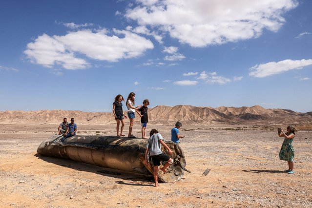 People stand on top of the remains of an Iranian missile in the Negev desert near Arad, on October 2, 2024, in the aftermath of an Iranian missile attack on Israel. Israel vowed to make Iran “pay” for firing a barrage of missiles at its territory, with Tehran warning on October 2 it would launch an even bigger attack it is targeted. (Photo by Menahem Kahana/AFP Photo)