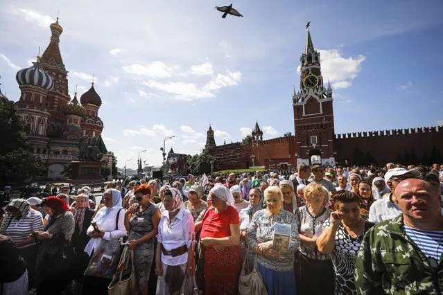 People listen to a prayer during celebrations for the day of St. Ilya and Paratroopers Day in Red Square in Moscow, Russia, Wednesday, August 2, 2017. Russian Paratroopers' Forces celebrate the 87th anniversary of the establishment of Russia's airborne forces. (Photo by Alexander Zemlianichenko/AP Photo)