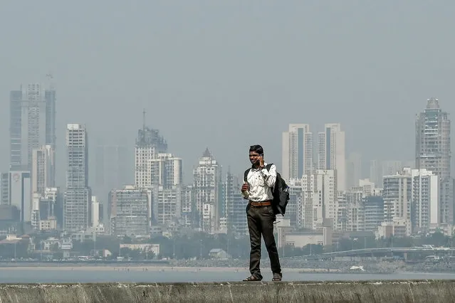 A man speaks on a mobile phone as he stands near the sea front overlooking the city skyline in Mumbai on February 18, 2020. (Photo by Punit Paranjpe/AFP Photo)