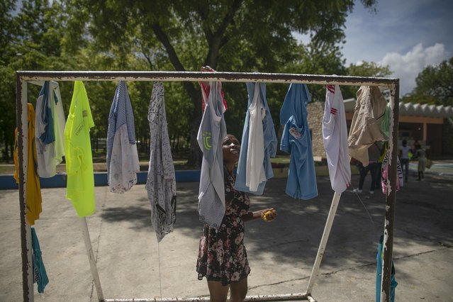 A woman hangs clothes to dry in a school turned into a shelter for families forced to leave their home in Cite Soleil due to clashes between armed gangs, in Port-au-Prince, Haiti, Saturday, July 23, 2022. (Photo by Joseph Odelyn/AP Photo)