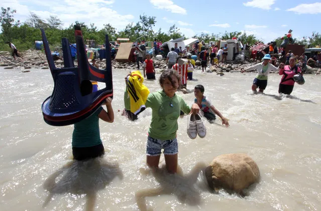 People cross the Tachira River from Venezuela, behind, to Colombia, on the border that separates San Antonio del Tachira, Venezuela, from Villa del Rosario, Colombia, Tuesday, August 25, 2015, during a mass exodus of Colombians. (Photo by Eliecer Mantilla/AP Photo)