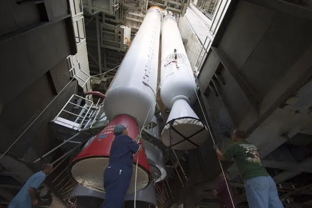 Inside the Vertical Integration Facility at Space Launch Complex 41 on Cape Canaveral Air Force Station in Florida, technicians using an overhead crane guide the final solid rocket motor into position for mating to the first stage of a United Launch Alliance Atlas V rocket. The Atlas V will carry NASA's Mars Science Laboratory (MSL) mission into space in a launch planned for November 26, 2011. (Photo by Jim Grossmann/NASA)