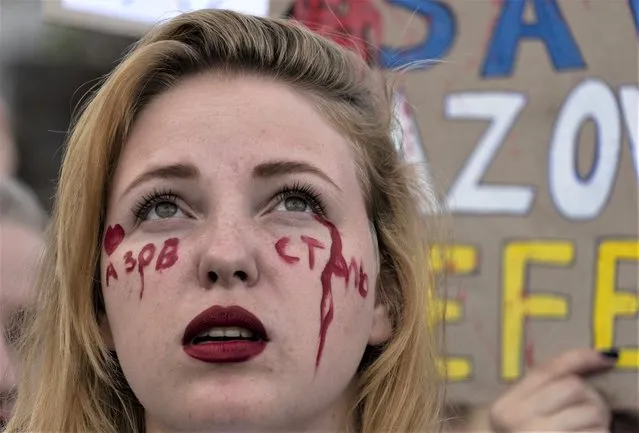 A relative with the writing “Above Steel” on her face attends a rally in support of Ukrainian soldiers from the Azov Regiment who were captured by Russia in May after the fall of Mariupol, in Kyiv, Ukraine, Thursday, August 4, 2022. The rally comes as U.S. officials believe Russia is working to fabricate evidence concerning last week's deadly strike on a prison housing prisoners of war in a separatist region of eastern Ukraine. (Photo by Efrem Lukatsky/AP Photo)