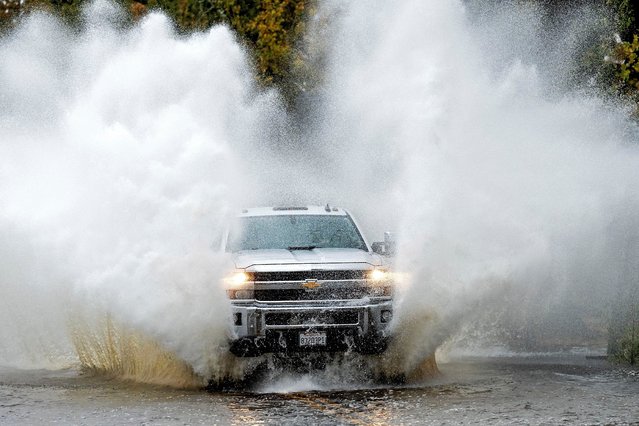 A pick-up truck drives through floodwaters as heavy rains fall in Windsor, Calif., on Friday, November 22, 2024. (Photo by Noah Berger/AP Photo)