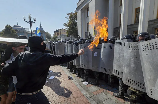Protesters against changes to Ukrainian Constitution clash with police in front of Ukrainian Parliament in Kiev, Ukraine, August 31, 2015 as lawmakers accepted the project to changing Ukrainian Constitution about decentralization of power in first reading. A grenade exploded outside Ukraine's parliament August 31 during a protest as legislators voted in favour of a draft law to give special status to the eastern regions that are locked in a conflict between the Ukrainian military and pro-Russian separatists. (Photo by Sergey Dolzhenko/EPA)