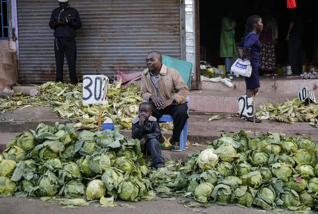 In this photo taken Tuesday, March 24, 2020, a street trader sells cabbages by the side of the road, after the government ordered the closure of the main open air market, in the Mathare slum, or informal settlement, of Nairobi, Kenya. (Photo by Brian Inganga/AP Photo)