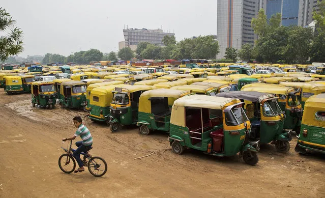 A young boy cycles past scores of three wheelers called autos parked during a commercial auto and taxi strike in New Delhi, India, Tuesday, July 26, 2016. The strike was called to urge the government to stop app based services like Uber and Ola from plying in the national capital. (Photo by Saurabh Das/AP Photo)