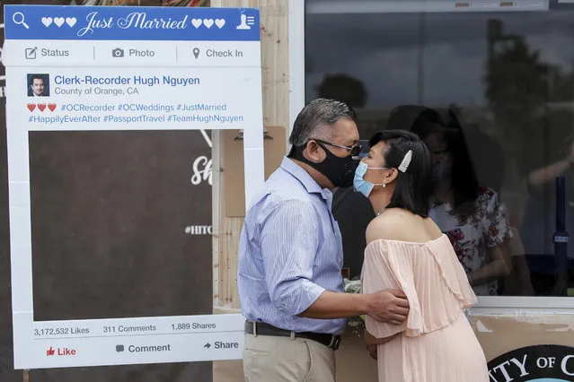Rodger Andrei Onate and Noelle Danielle Francisco kiss through their masks after taking their wedding vows over a two-way radio in a parking lot after marriage services resumed for couples whose nuptials were postponed during the outbreak of the coronavirus disease (COVID-19) in Anaheim, California, U.S., April 17, 2020. (Photo by Mike Blake/Reuters)