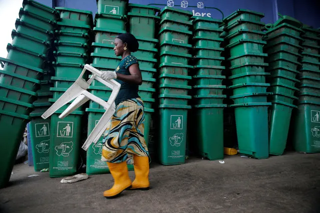 A woman carries a plastic chair as she walks past a pile of litter bins at Wecycler recycling  centre in Ebutte Meta district in Lagos, Nigeria July 28, 2016. (Photo by Akintunde Akinleye/Reuters)