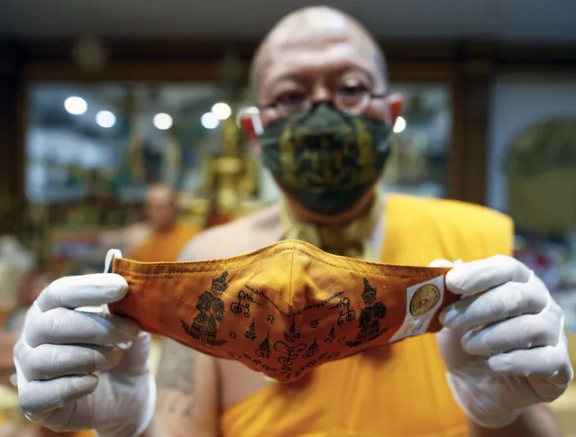 Thai Buddhist abbot monk Phra Kru Palad Sitthiwat, known as Luang Phi Namfon, shows a face mask he inscribed with spiritual incantations at Wat Phai Lom in Nakhon Pathom province, Thailand, 29 March 2020. Luang Phi Namfon inscribed spiritual incantations on face masks made by villagers and sold by the abbot, aimed to protect devotees from the growing fear of people in the wake of the coronavirus COVID-19 pandemic. More than 100,000 of the talisman protective masks have been sold across Thailand. Seven people have died in the country since the beginning of the coronavirus outbreak, and more than 1,300 COVID-19 infections have been reported so far. (Photo by Rungroj Yongrit/EPA/EFE)