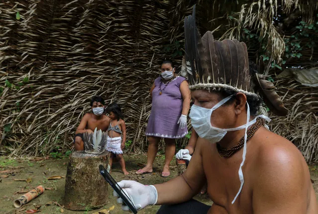 Satere-mawe indigenous people are seen using a smartphone to contact a doctor in Sao Paulo state to receive medical guidance amid the COVID-19 novel coronavirus pandemic at the Sahu-Ape community, 80 km of Manaus, Amazonas State, Brazil, on May 5, 2020. The Brazilian state of Amazonas, home to most of the country's indigenous people, is one of the regions worst affected by the pandemic, with more than 500 deaths to date according to the health ministry. (Photo by Ricardo Oliveira/AFP Photo)