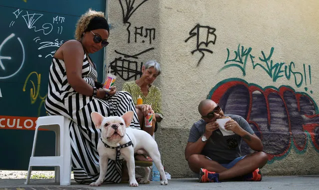 People eat street market-purchased food and drinks including pasteis de feira (pastries) in Rio de Janeiro, Brazil, May 7, 2016. (Photo by Sergio Moraes/Reuters)