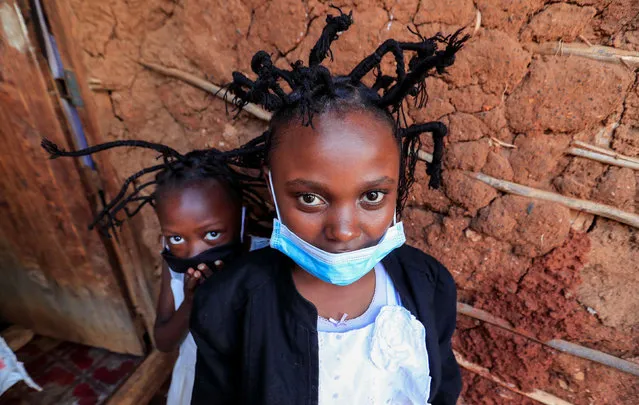 Martha Apisa, 12, and Stacy Ayuma, 8, pose for a photograph outside their house after plaiting with the "coronavirus" hairstyle, designed to emulate the prickly appearance of the virus under a microscope, as a fashion statement against the spread of the coronavirus disease (COVID-19), at Mama Brayo Beauty Salon within Kambi-Muru village of Kibera slums in Nairobi, Kenya on April 29, 2020. (Photo by Thomas Mukoya/Reuters)