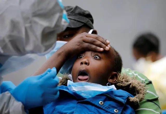 A young girl reacts as a Kenyan ministry of health medical worker takes a swab during mass tasting in an effort to fight against the spread of the coronavirus disease (COVID-19) in the Kawangware neighborhood of Nairobi, Kenya, May 2, 2020. (Photo by Baz Ratner/Reuters)
