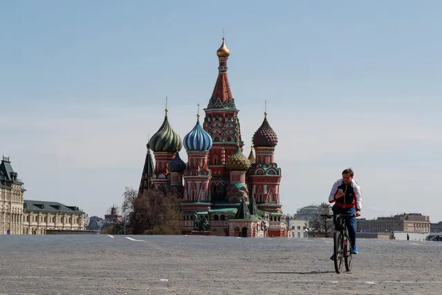 A man rides a bicycle along empty Red Square near St. Basil's Cathedral in central Moscow, Russia on May 1, 2020. Russia marks the Spring and Labour Day without traditional demonstrations and celebrations due to the coronavirus disease (COVID-19) outbreak. (Photo by Shamil Zhumatov/Reuters)