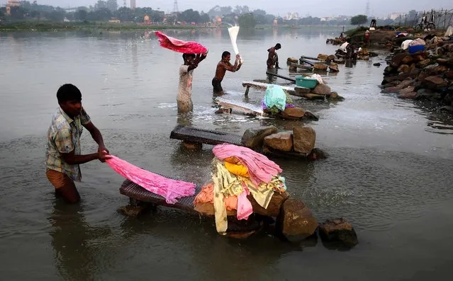 Dhobis, or washermen, wash clothes on the banks of the River Gomti in Lucknow, India, Wednesday, September 17, 2014. Dhobis are traditional laundry workers who wash clothes by hand and dry them in the sun, an occupation which has been in existence for generations. (Photo by Rajesh Kumar Singh/AP Photo)
