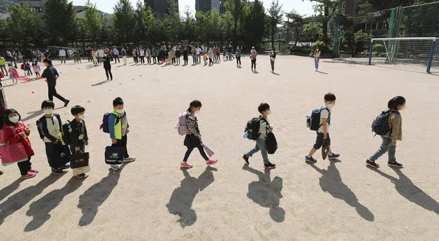 Students wearing face masks as a precaution against the new coronavirus, walk to their classrooms while maintaining social distancing after they attend the entrance ceremony at Chungwoon elementary school in Seoul, South Korea, Wednesday, May 27, 2020. More than 2 million high school juniors, middle school seniors, first- and second-grade elementary school children and kindergartners were expected to return to school on Wednesday. (Photo by Lee Jin-wook/Yonhap via AP Photo)