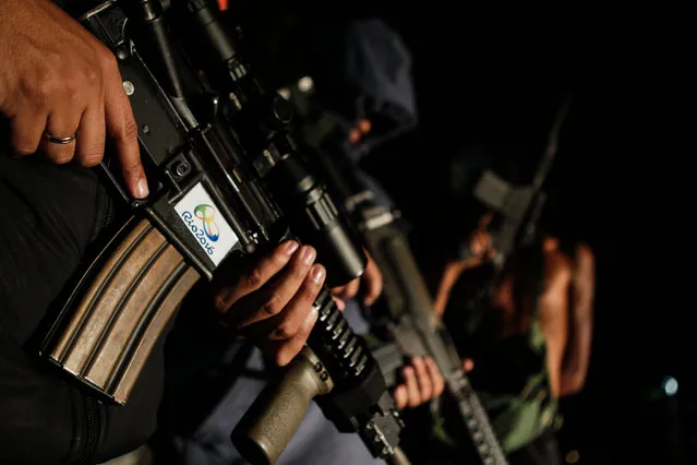 Young men presenting themselves as drug traffickers pose with assault rifles decorated with a Rio 2016 sticker in a favela of Rio de Janeiro late August 20,2016, a night before the end of the Olympic Games. Security worries have never been far away of the Rio 2016 Olympic Games in a city known for its violent crime. (Photo by Diego Herculano/AFP Photo)