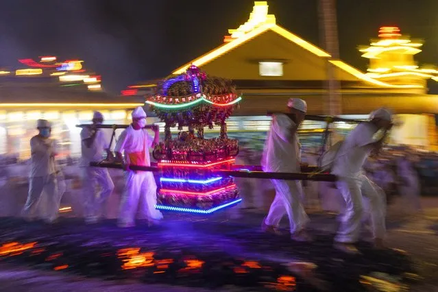 Malaysian Chinese, carrying an Emperor God, walk barefoot over burning coals on the final day of the Nine Emperor Gods festival at a temple in Kuala Lumpur, Tuesday, October 4, 2022. The men have abstained from meat for the past nine days in order to purify their bodies in preparation for this painful ritual, in which women are barred from participating. (Photo by Vincent Thian/AP Photo)