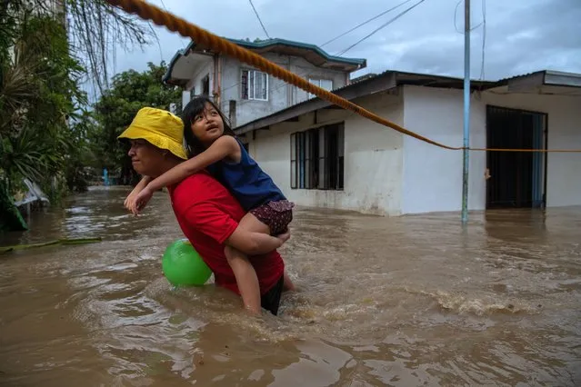 Residents wade through flood waters that barreled through their village on October 30, 2022 in Kawit, Philippines.  (Photo by Jes Aznar/Getty Images)