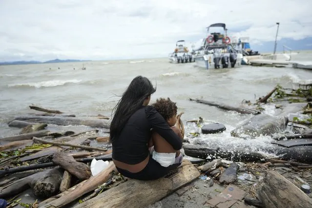 Venezuela migrant Yusney Velandia and her child watch boats that carry migrants to Acandi from Necocli, Colombia, Thursday, October 13, 2022, as she considers continuing her journey north. Some Venezuelans are reconsidering their journey to the U.S. after the U.S. government announced on Oct. 12 that Venezuelans who walk or swim across the border will be immediately returned to Mexico without rights to seek asylum. (Photo by Fernando Vergara/AP Photo)