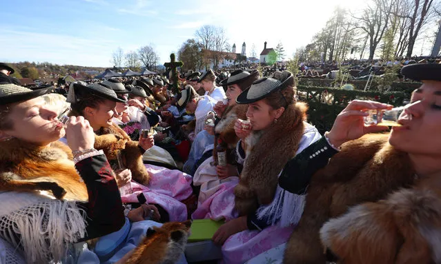 Participants from the farming community, dressed in traditional Bavarian clothing, drink schnapps in a wooden carriage on the way to the chapel on the Kalvarienberg during the Leonhardi Ritt procession, to pray to St Leonhard, the patron saint of animals, in Bad Toelz, Germany on November 7, 2022. (Photo by Lukas Barth/Reuters)