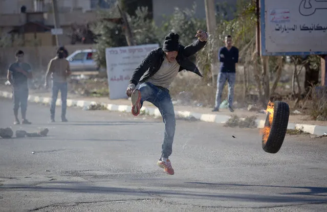 A Palestinian protester kick a tire during clashes with Israeli troops in the village of Qusra, near the West Bank City of Nablus, Thursday, November 30, 2017, after a Jewish West Bank settler fatally shot a 47-year-old Palestinian villager in a clash that occurred under disputed circumstances. (Photo by Majdi Mohammed/AP Photo)