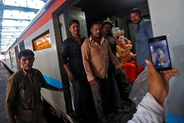 People pose for a picture with an idol of Hindu elephant god Ganesh, the deity of prosperity, on a train at a railway station in Mumbai, India August 29, 2016. (Photo by Danish Siddiqui/Reuters)