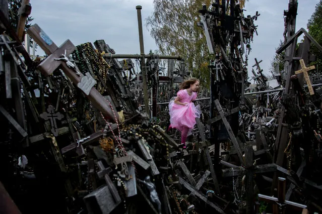 “Cross and Girl”. A girl ran through the hill of cross. Photo location: Siauliai, Lithuania. (Photo and caption by Hideki Mizuta/National Geographic Photo Contest)