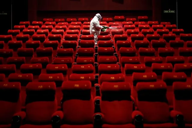 A worker wearing protective gear sprays disinfectant inside an empty PVR multiplex that was closed in New Delhi, India July 31, 2020. (Photo by Adnan Abidi/Reuters)