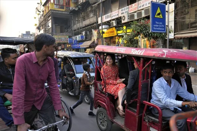 A cycle rickshaw puller looks on as German Foreign Minister Annalena Baerbock, center, rides on an e-rickshaw during her tour of Chandni Chowk, in the old quarters of New Delhi, India, Monday, December 5, 2022.  Baerbock is on a two day visit to India. (Photo by Manish Swarup/AP Photo)