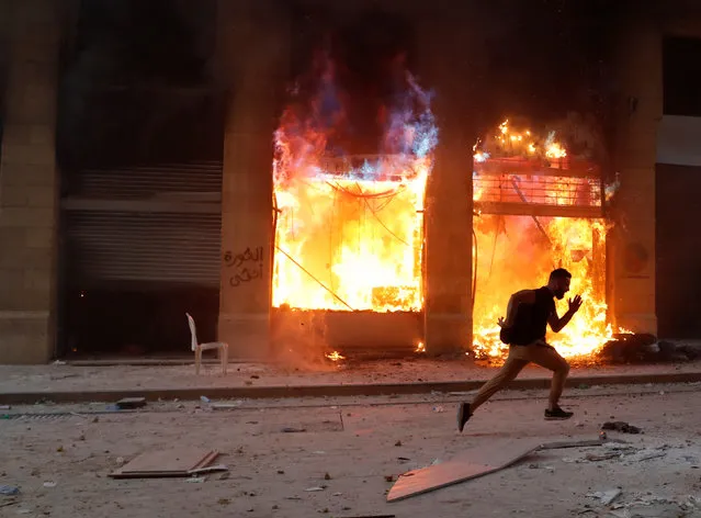 A protester runs away from security forces, in front of a burning building during a protest in Beirut, Lebanon, August 8, 2020. (Photo by Goran Tomasevic/Reuters)