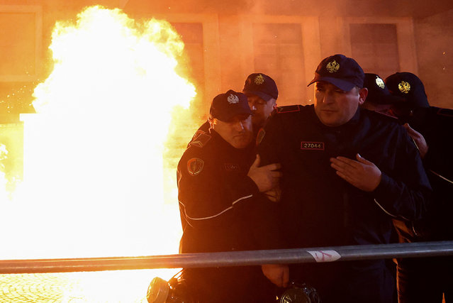 Police officers stand guard while a fire burns, as supporters of the opposition attend an anti-government protest in front of Prime Minister Edi Rama's office in Tirana, Albania, on February 20, 2024. (Photo by Florion Goga/Reuters)