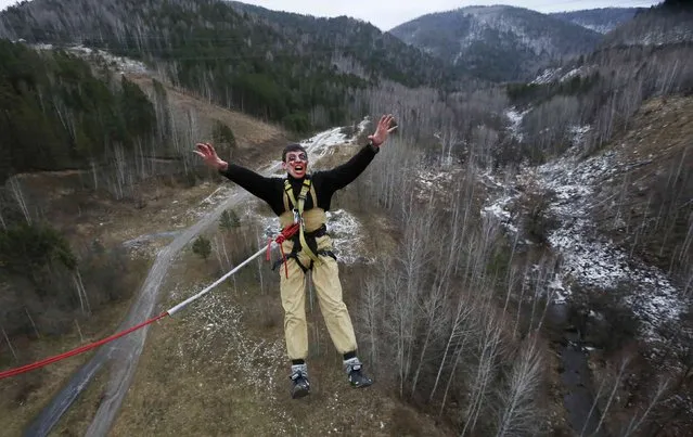 A member of the amateur rope-jumping group “Exit Point” wears Halloween make-up as he jumps from a 44-metre high (144-ft) water pipe bridge in the Siberian Taiga area outside Krasnoyarsk, November 2, 2014. (Photo by Ilya Naymushin/Reuters)