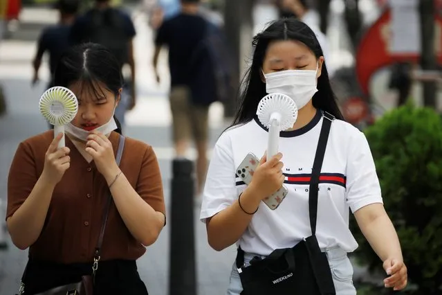Women wearing masks to prevent the spread of the coronavirus disease (COVID-19) use portable fans to cool down in Seoul, South Korea, August 20, 2020. (Photo by Kim Hong-Ji/Reuters)