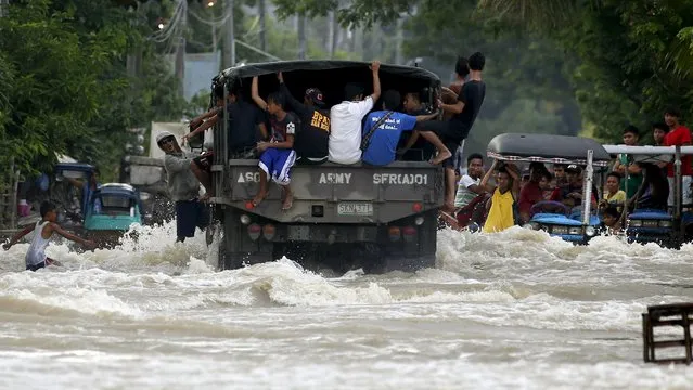 Typhoon victims are transported on a military truck along a flooded portion of a highway in Zaragoza, Nueva Ecija in northern Philippines October 20, 2015, after the province was hit by Typhoon Koppu. (Photo by Erik De Castro/Reuters)