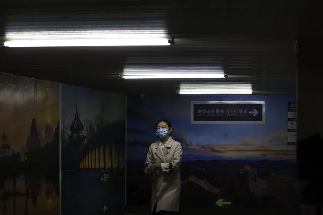 A woman wearing a face mask to help curb the spread of the coronavirus walks by pictures of China's tourism destination on display inside an underpass tunnel in Beijing, Monday, October 19, 2020. (Photo by Andy Wong/AP Photo)