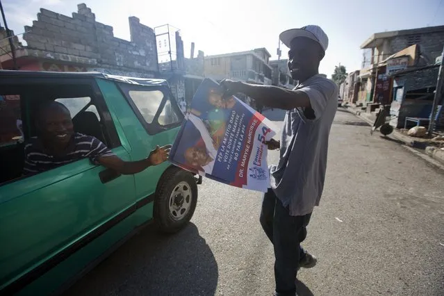 A supporter of Maryse Narcisse gives out campaign posters promoting the presidential candidate, in Port-au-Prince, Haiti, Tuesday, August 23, 2016. Campaign season begins yet again for Haiti as authorities organize a redo of last year's presidential vote. (Photo by Dieu Nalio Chery/AP Photo)