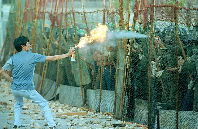 A South Korean student sprays a flaming aerosol can as riot police respond with a fire extinguisher during an anti-government demonstration at Yonsei University in Seoul, Korea, June 15, 1987. (Photo by Itsuo Inouye/AP Photo)