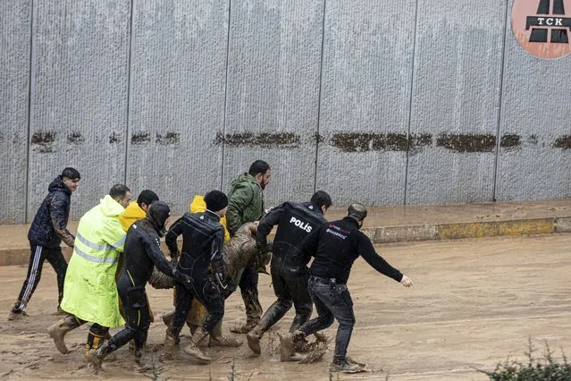 Police and rescue team members carry the body of a person during floods after heavy rains in Sanliurfa, Turkey, Wednesday, March 15, 2023. Floods caused by torrential rains hit two provinces that were devastated by last month's earthquake, killing at least 10 people and increasing the misery for thousands who were left homeless, officials and media reports said Wednesday. At least five other people were reported missing. (Photo by Ugur Yildirim/DIA via AP Photo)