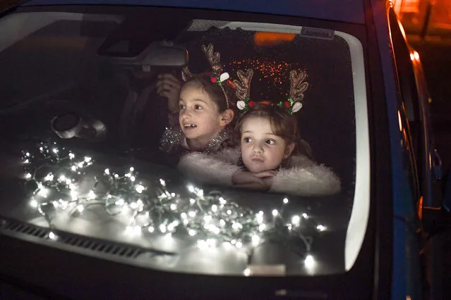 Two young girls look out of the car window as pupils, parents and guardians attend the Kilgarston Girls School drive-in movie on December 10, 2020 in Perth, Scotland. The school is putting on a Covid Christmas Movie, involving all 260 pupils and 100 staff, recorded over two weeks and shown tonight during three performances. (Photo by Jeff J. Mitchell/Getty Images)
